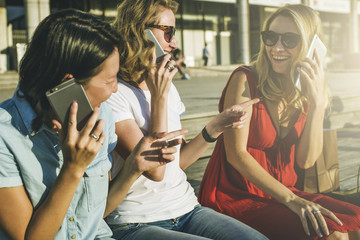 Sticker - Three laughing girls sitting outside on wooden steps and 
talking on cellphone.One girl dressed in red dress, talking on tablet 
computer.Meeting friends.Young women using gadgets.