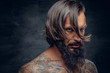 © Fxquadro - Bearded male with long hair and tattooed chest.
