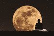 Silhouette a man sitting relaxing under full moon at night with stars on the sky
