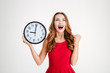 Woman in red dress holding wall clock and celebrating success