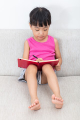 Wall Mural - Asian Chinese little girl sitting on the sofa writting book