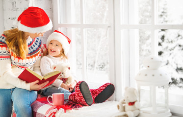 Sticker - happy family mother and child daughter reading book on winter wi