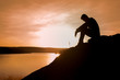 © ittipol - Silhouette of young man sitting on sunset or sunrise,