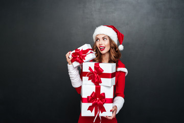 Poster - Woman in red santa claus dress holding stack of gifts