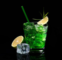 Wall Mural - Green tarragon drink with ice cubes, lime on a black  background