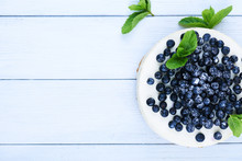 Sweet Creamy Blueberry Cheesecake With Fresh Blueberries And Mint Leaves On A White Wooden Background With Copy Space.