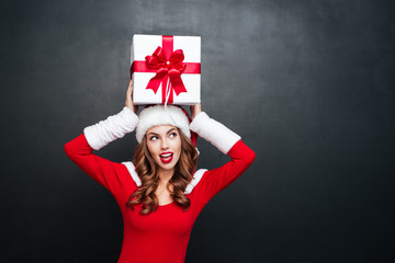 Wall Mural - Woman in red dress holding gift box above her head