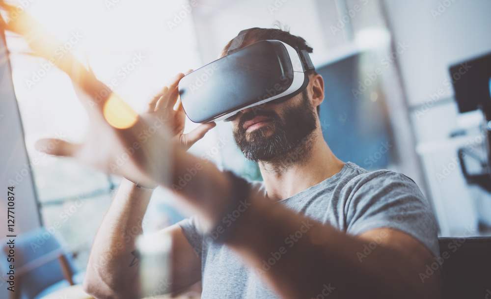 Closeup of bearded young man wearing virtual reality goggles in modern ...