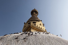 Swayambhunath Ancient Buddhist Religious Complex Atop A Hill In The Kathmandu Valley, Nepal. Pigeons Sitting On The White Dome Under The Golden Top Of Swayambhunath Stupa.