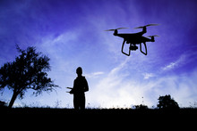Silhouette Of Man With Flying Drone In Nature At Dusk.