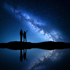 Wall Mural - milky way with silhouette of a family. father and a son who pointing finger in night starry sky on t