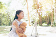 © palidachan - Asia little girl with doll bear  sitting on a swing at The park.