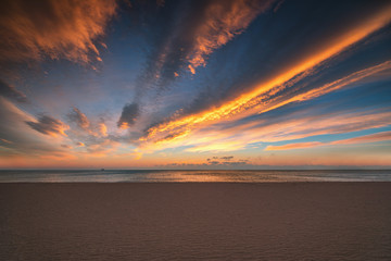 Sandy beach, colorful sunrise with beautiful cloudscape