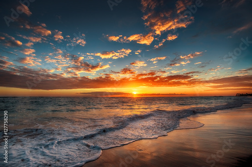 Leinwand Poster Sunrise over the beach. Waves washing the sand.