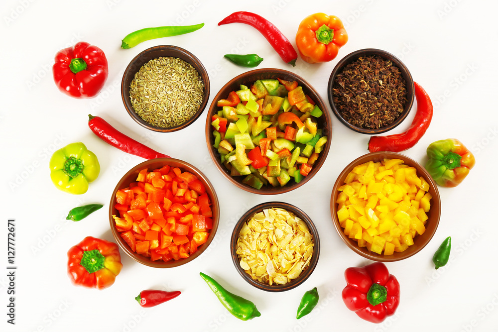 Chopped bell pepper in bowls and chili pepper isolated on white