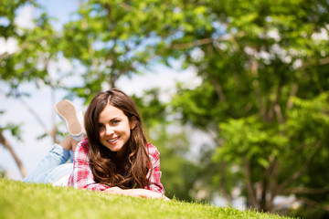 Wall Mural - beautiful smiling woman lying on a grass outdoor.