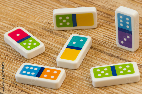 Domino pieces on the wooden table background плакат