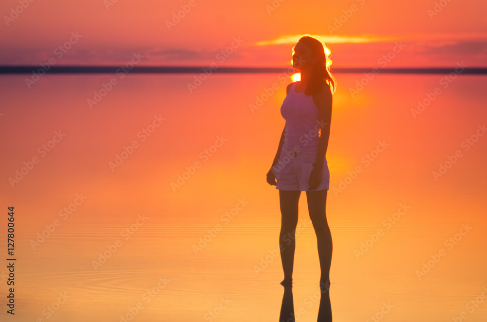 Beautiful female model stands in front of sun goes behind horizon at ...