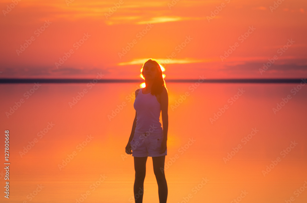 Beautiful female model stands in front of sun goes behind horizon at ...