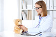 © rogerphoto - Female doctor examining a .Teddy bear  patient by stethoscope. Children medical care concept