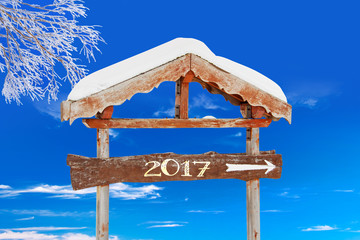 Wall Mural - 2017 written on a wooden direction sign, blue sky and frozen tree background