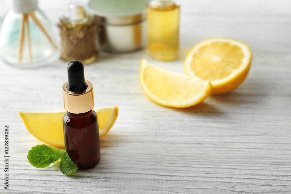 Beautiful spa composition with lemon essential oil on white wooden background, closeup