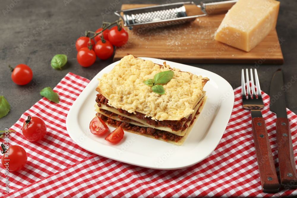 Plate with portion of tasty lasagna on napkin
