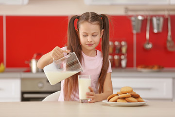 Wall Mural - Cute little girl pouring fresh milk into glass at kitchen