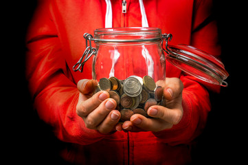 Wall Mural - Woman in red sweatshirt holding money jar with coins