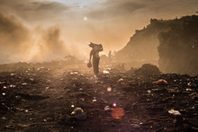 A Waste Picker Is Collecting Reusable Or Recyclable Materials In A Open Burning Dump.