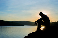 Sad Young Man Silhouette Worried On The Stone At Sunset ,Silhouette Concept