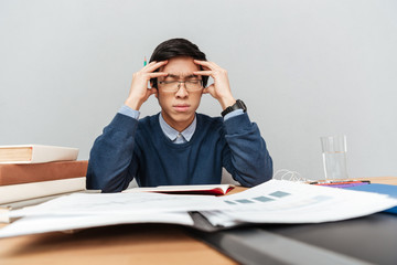 Poster - Thoughtful asian student sits by the table