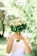 © IVASHstudio - bride hiding behind a wedding bouquet of flowers