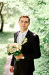 © IVASHstudio - young handsome groom in a black suit standing alone outdoors