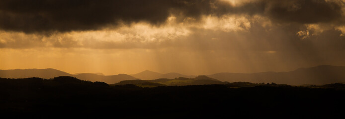 Dramatic panorama. sun beams bursting through dark stormy clouds. Czech Central Mountainc, aka Ceske Stredohori, Czech Republic