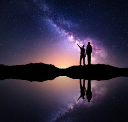 Wall Mural - milky way with silhouette of a family. father and a son who pointing finger in night starry sky on t