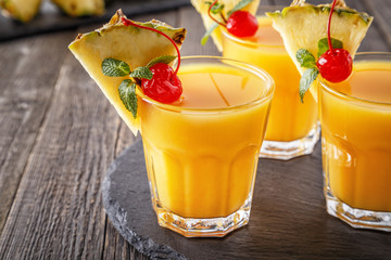 Glasses of pineapple juice with pieces of pineapple