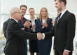 © ASDF - Mature businessman shaking hand of  his partner with colleagues