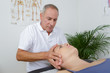 physiotherapist massages holding male clients head