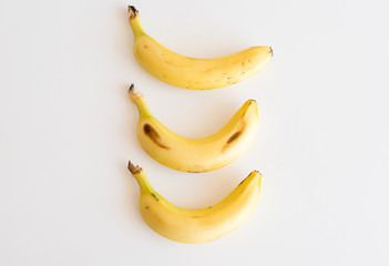 High angle view of three bananas arranged vertically on white table