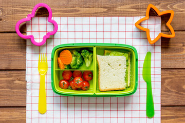 green lunch box for kid on wooden background top view