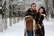© alexkich - beautiful young couple in a snowy park wrapped