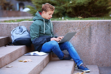 Poster - Teenager with laptop sitting on steps outdoors