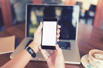 girl using smart phone in cafe. hand holding smart phone white screen. black color smart phone vintage tone. hand holding using mobile phone on sunset...