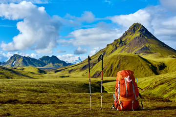 backpack and Trekking Poles on the trail in the Islandic mountains. Trek in National Park Landmannalaugar, Iceland. valley is covered with bright green moss