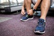 © WavebreakMediaMicro - Lower section of man sitting on treadmill and tying the shoelace
