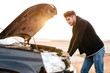 © Drobot Dean - Young casual man trying to fix his broken car