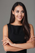 © Drobot Dean - Smiling beautiful woman in black dress standing with arms folded
