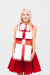 Wall Mural - Happy young woman in red dress holding stack of presents