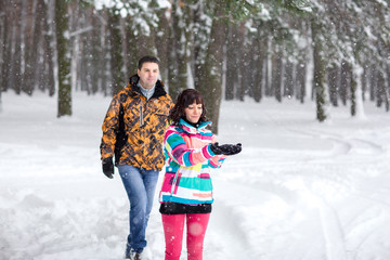  Winter christmas, young woman and man catches snowflakes hands in winter forest